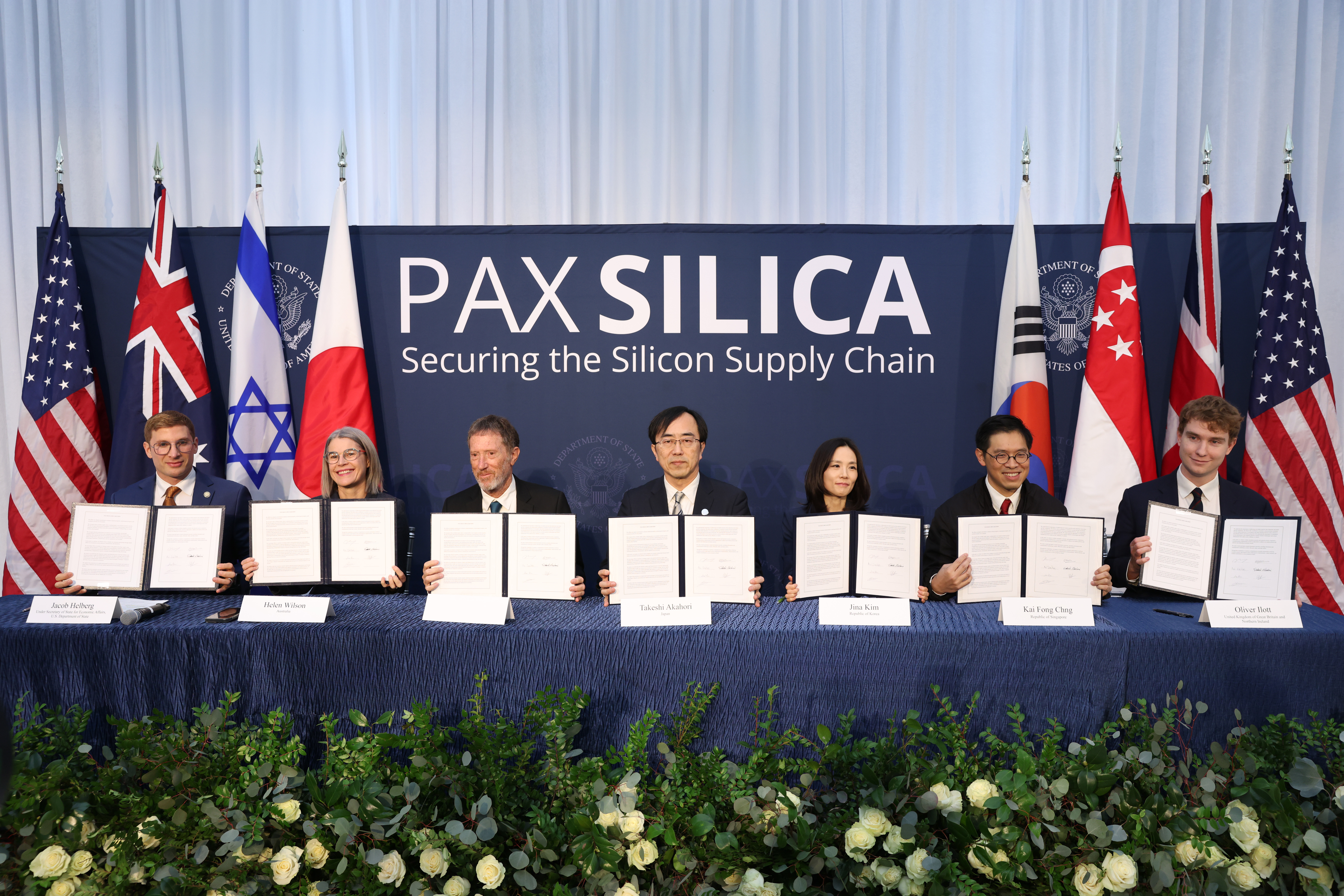 A group of politicians and business leaders hold up a signature at The Pax Silica Summit.